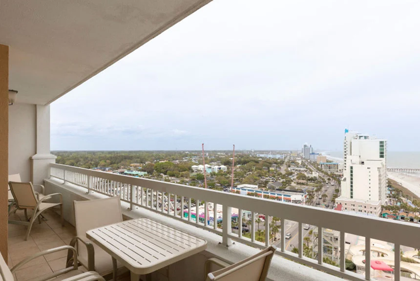 Balcony with a table and chairs overlooking the city and coast at a Westgate Myrtle Beach Oceanfront one-bedroom ocean view