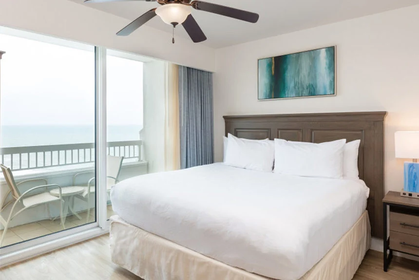 Bedroom in a Westgate Myrtle Beach Oceanfront one-bedroom ocean view with a bed, ceiling fan and balcony doors