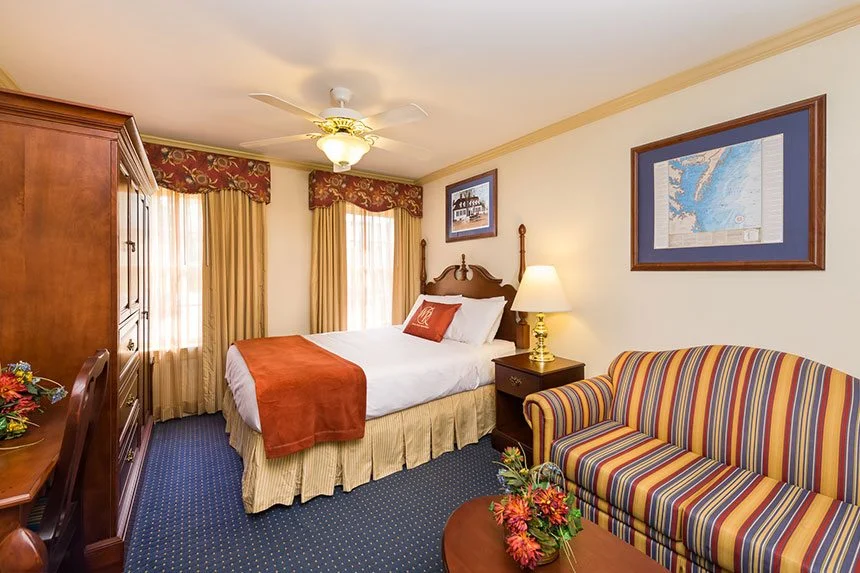 Bedroom of a Westgate Historic Williamsburg Resort two-bedroom deluxe villa with a bed, striped sofa and armoire