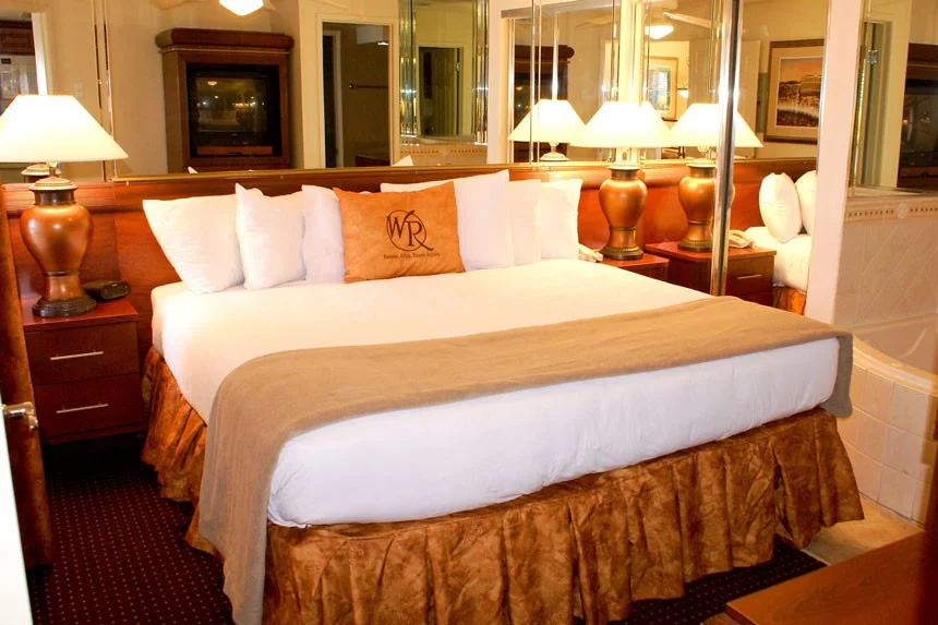 Bedroom of a Westgate Flamingo Bay one-bedroom villa with a bed, orange lamps and mirrored closet doors