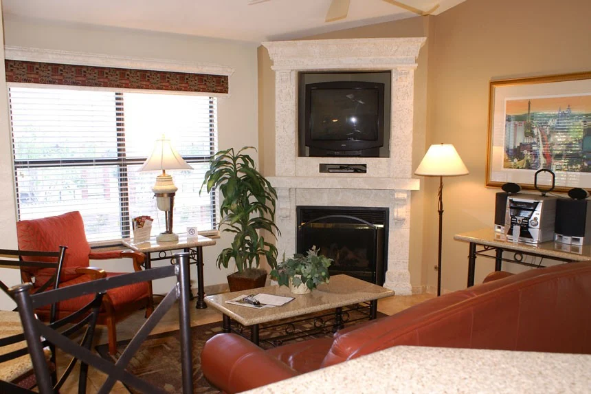 Living room of a Westgate Flamingo Bay one-bedroom villa with a corner fireplace, TV and red sofa
