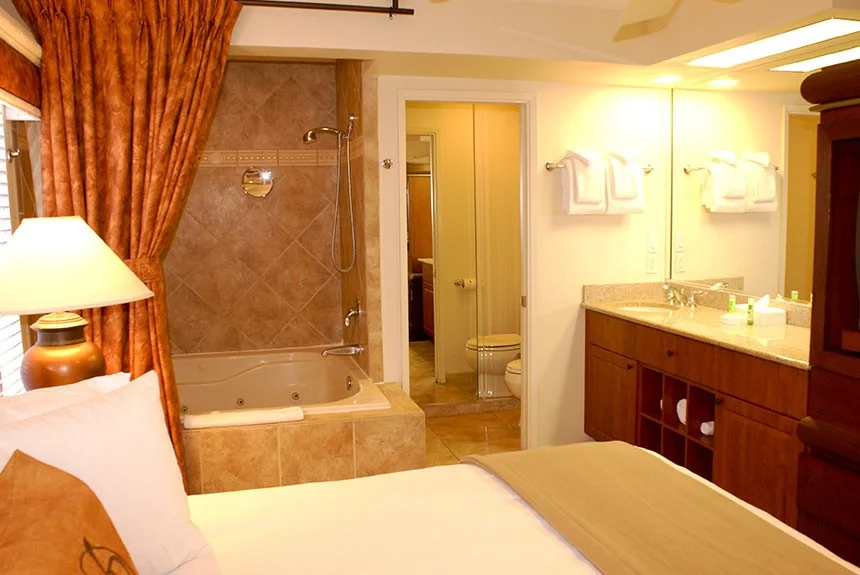 Bedroom of a Westgate Flamingo Bay two-bedroom villa open to a tiled shower and bathroom vanity