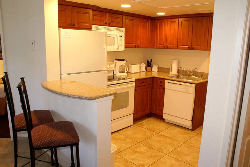 Kitchen in a Westgate Flamingo Bay two-bedroom villa with wood cabinets, white appliances and a breakfast bar