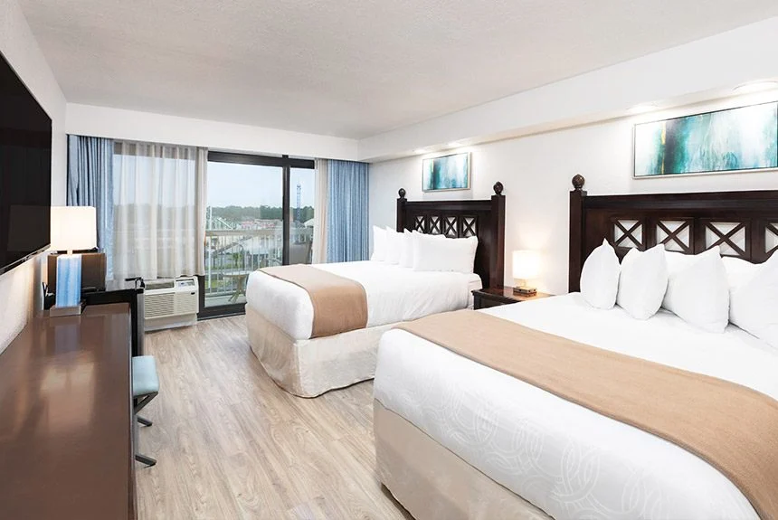 Two beds with dark headboards, a desk and balcony doors in a Westgate Myrtle Beach Oceanfront double amusement park view room