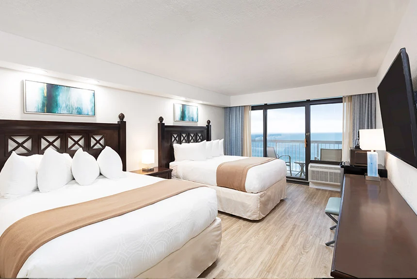 Two beds, a desk and wall TV facing ocean-view balcony windows in a Westgate Myrtle Beach Oceanfront double oceanfront room