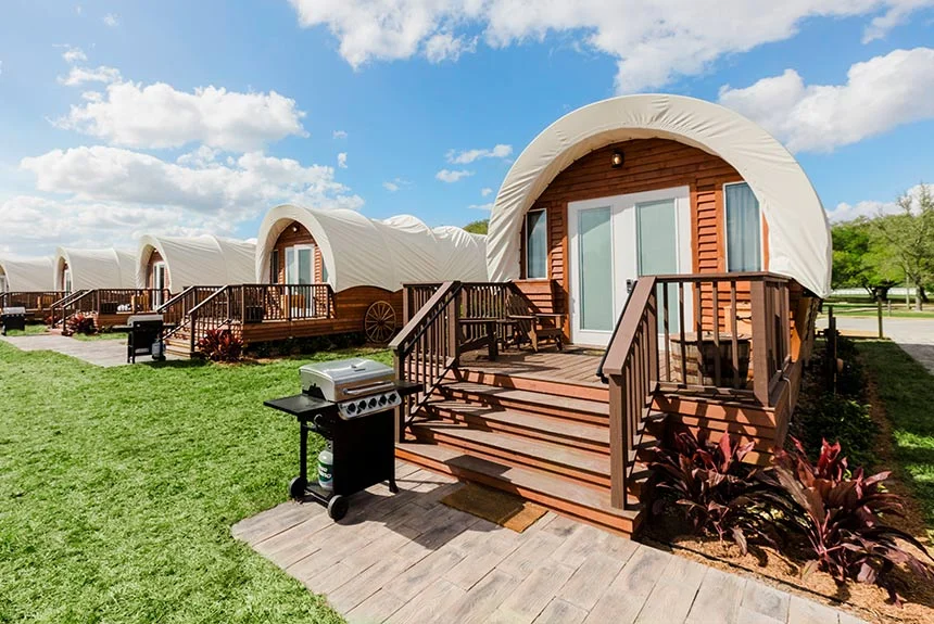 Row of luxe Conestoga wagons at Westgate River Ranch Resort with wooden steps, decks and a grill on the lawn
