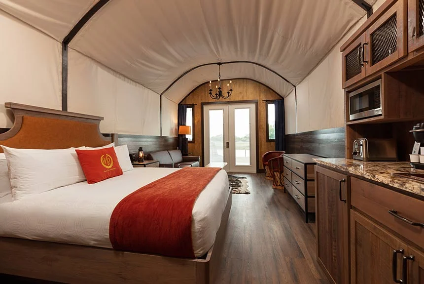 Bed, kitchenette with microwave and French doors under the canvas roof of a Westgate River Ranch Resort luxe Conestoga wagon