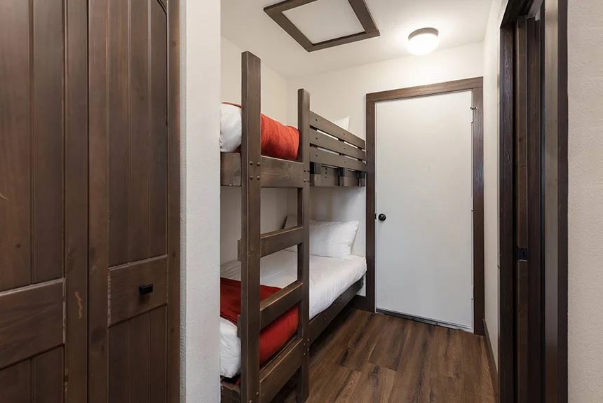 Bunk beds beside a wooden barn door inside a Westgate River Ranch Resort luxe Conestoga wagon