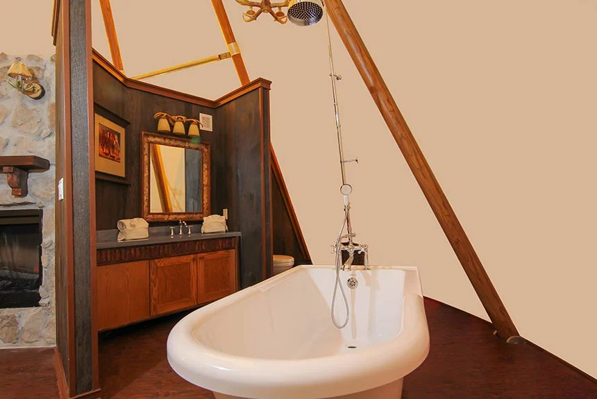 Freestanding bathtub with a handheld shower and a wood vanity with mirror in a Westgate River Ranch Resort luxe teepee