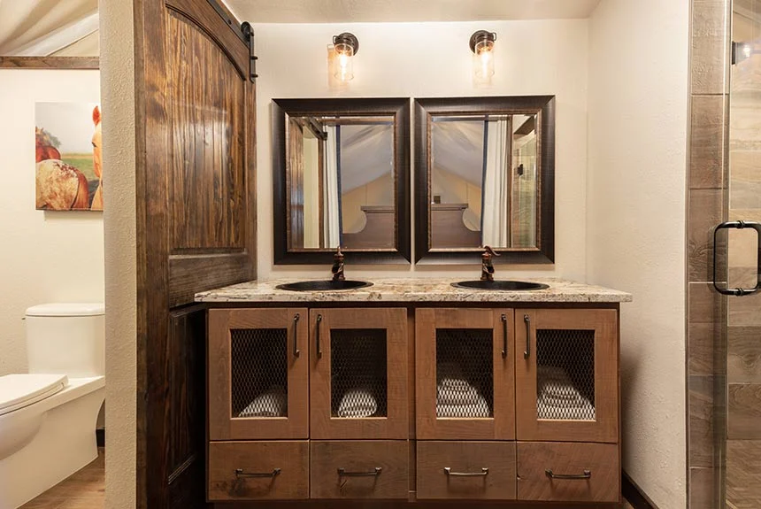 Bathroom in a Westgate River Ranch Resort luxury glamping tent with a double vanity, sliding barn door and glass shower