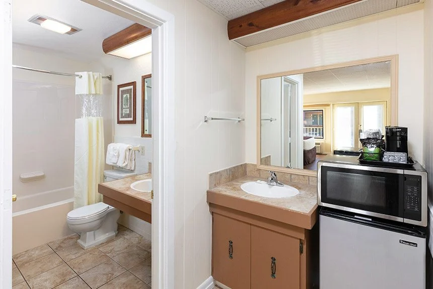 River Terrace Resort hotel bathroom with a tub and toilet beside a vanity, microwave and mini fridge