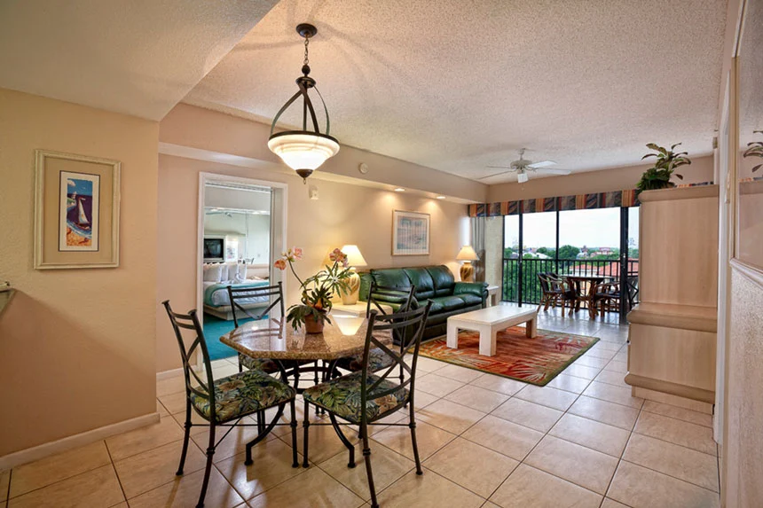 Dining area and living room with a green sofa and balcony doors in a Westgate Towers Resort one-bedroom villa