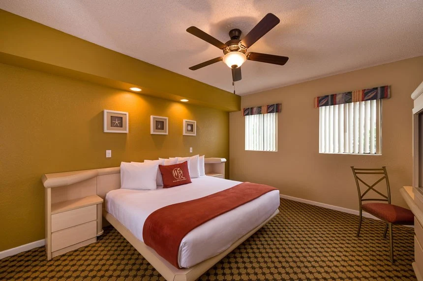 Bedroom of a Westgate Towers Resort one-bedroom villa with a bed, ceiling fan and gold-painted walls