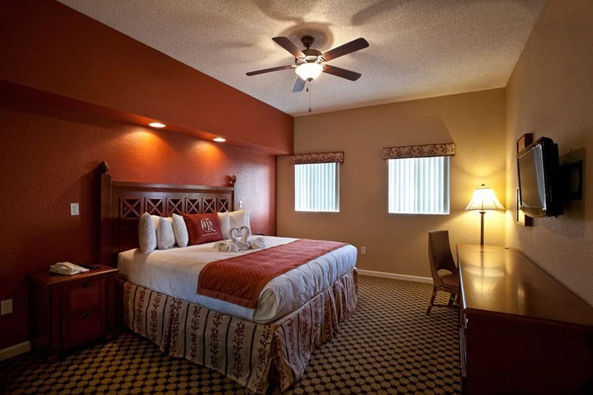 Bedroom of a Westgate Towers Resort two-bedroom villa with a red accent wall, bed and wall-mounted TV