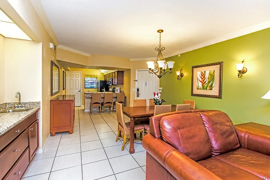 Living and dining area of a Westgate Lakes three-bedroom villa with a leather sofa, chandelier and green accent wall