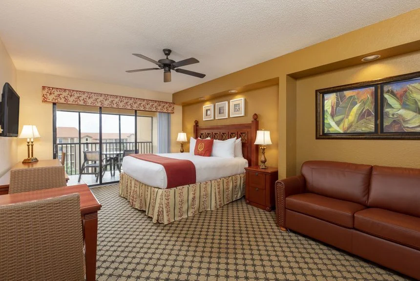 Westgate Lakes studio suite with a bed, red sofa and sliding doors to a balcony