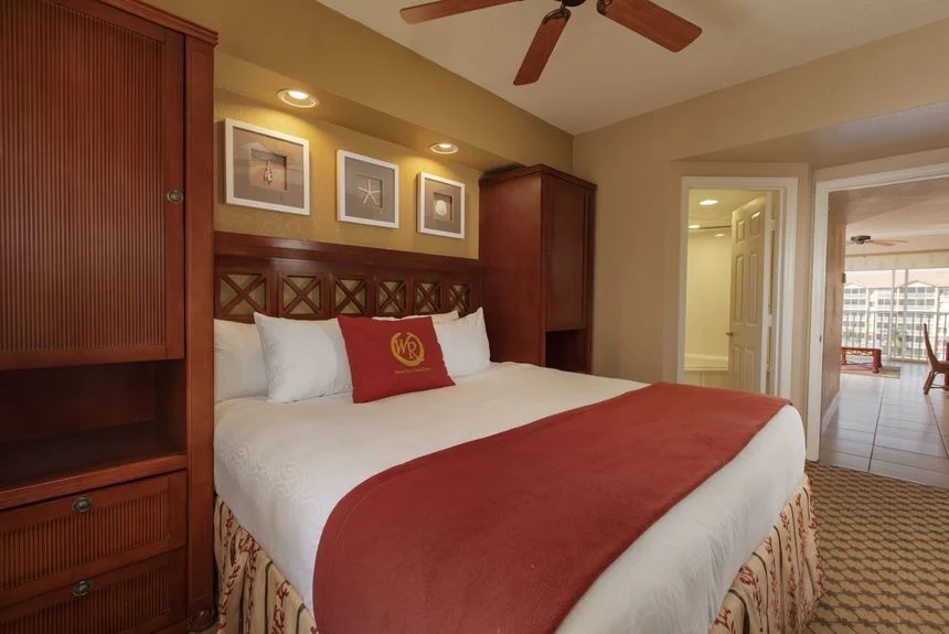 Westgate Town Center Resort studio deluxe with a bed, carved headboard, framed pictures and a wood armoire