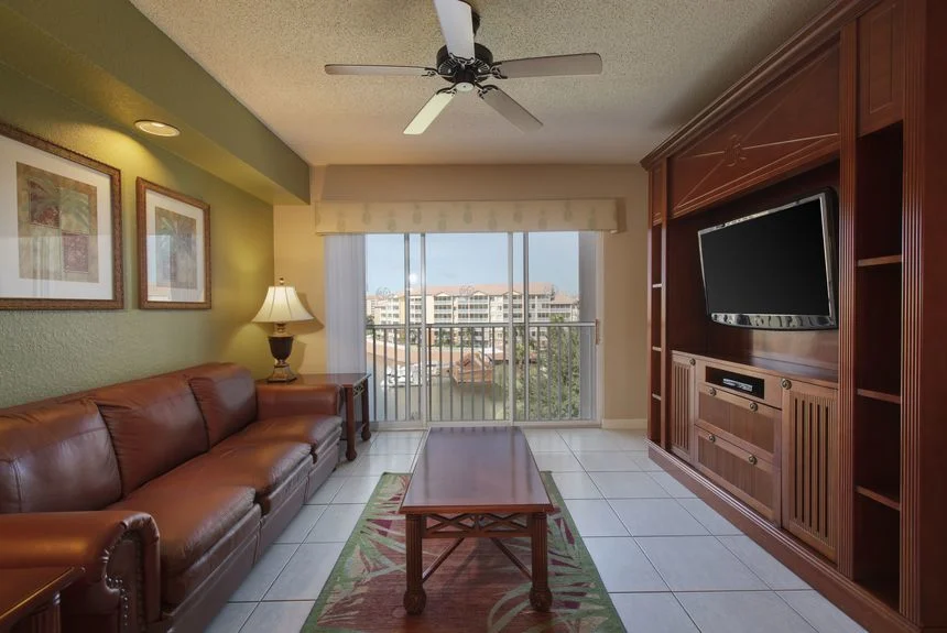 Westgate Town Center Resort studio deluxe living area with a leather sofa, TV cabinet and sliding doors to a balcony
