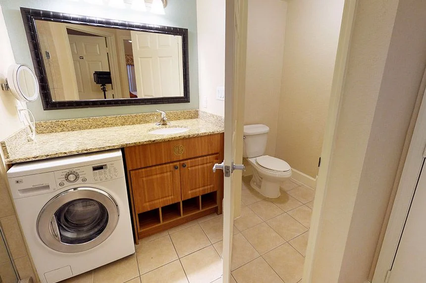 Bathroom of a Westgate Town Center Resort one-bedroom villa with a vanity, front-loading washer and toilet