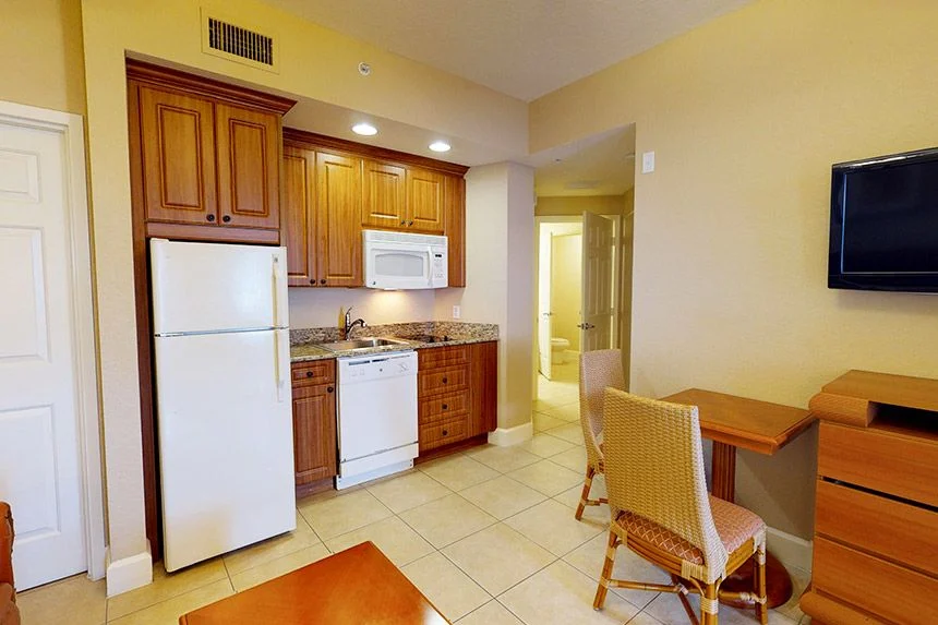 Kitchen of a Westgate Town Center Resort one-bedroom villa with wood cabinets, white appliances and a desk