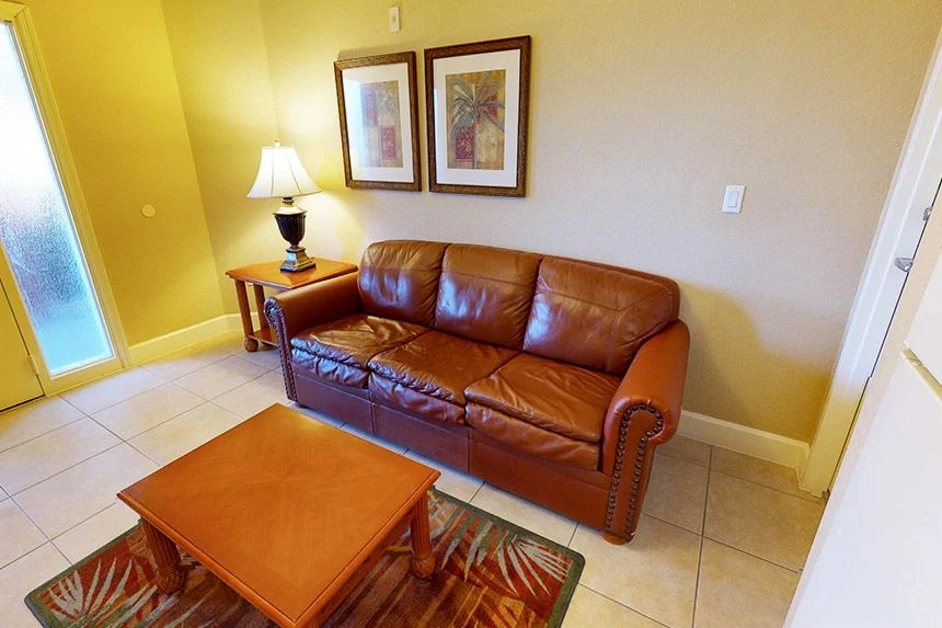 Living room of a Westgate Town Center Resort one-bedroom villa with a leather sofa, coffee table and framed art