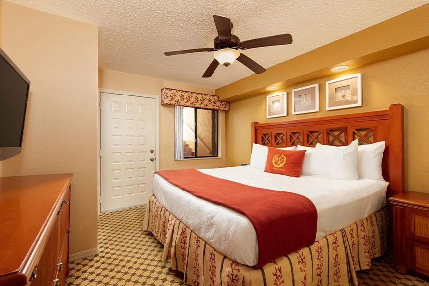 Bedroom of a Westgate Vacation Villas Resort one-bedroom villa with a carved headboard, red throw and ceiling fan
