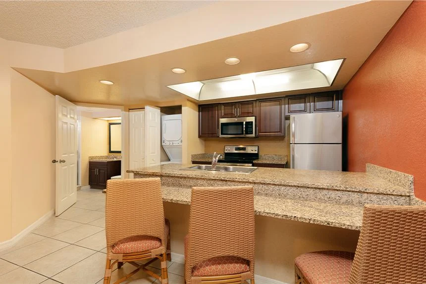 Kitchen in a Westgate Vacation Villas Resort one-bedroom villa with a granite breakfast bar, stools and stainless appliances