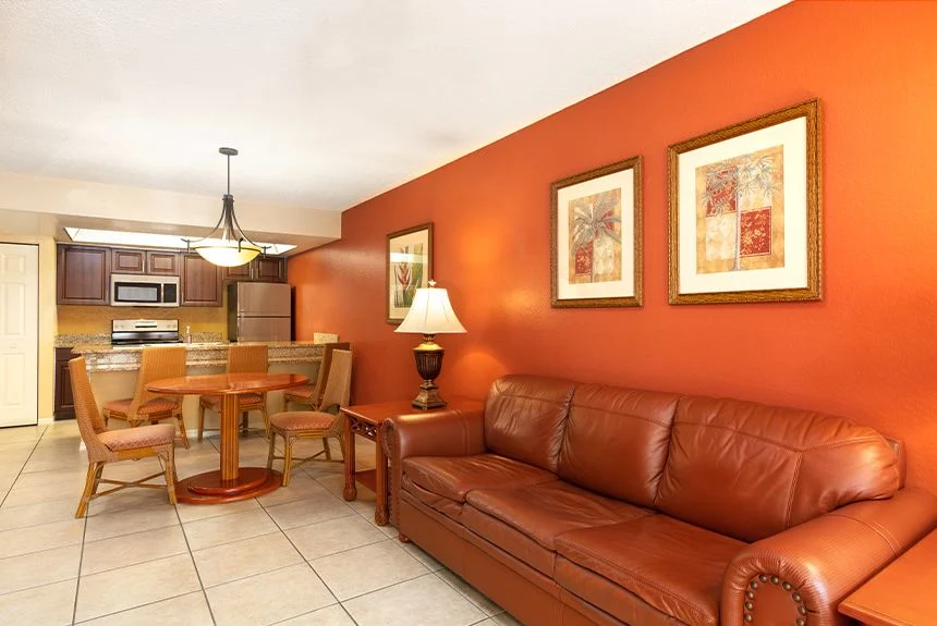 Living room of a Westgate Vacation Villas Resort one-bedroom villa with a leather sofa, red accent wall and dining area