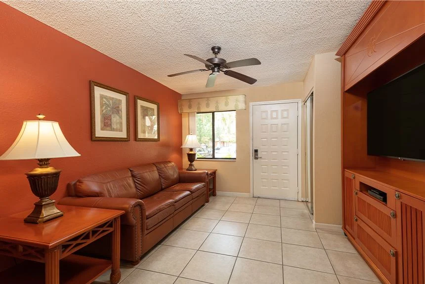 Westgate Vacation Villas Resort one-bedroom villa living area with a leather sofa, table lamp and TV cabinet