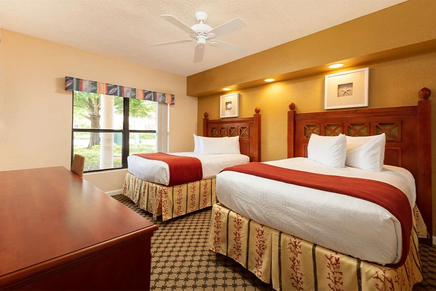 Westgate Vacation Villas Resort studio with two beds in red and white bedding, carved headboards and a ceiling fan