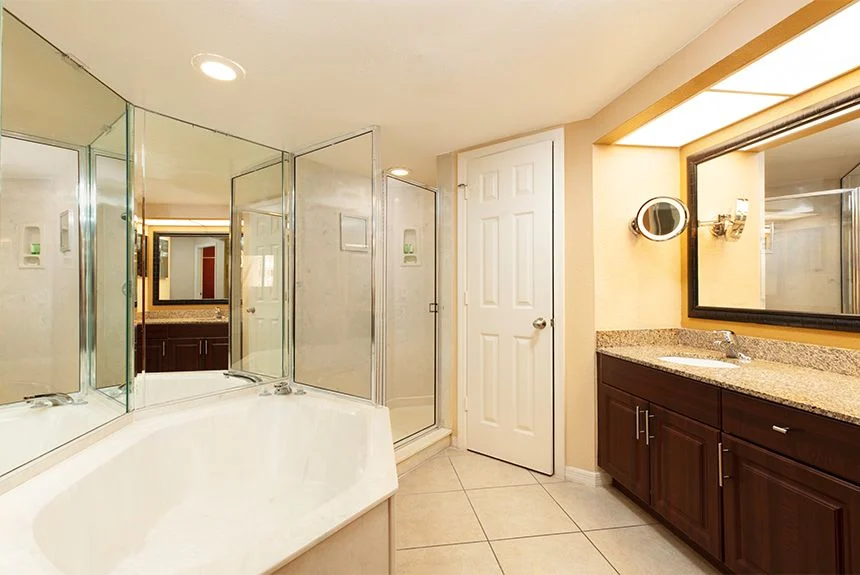 Bathroom of a Westgate Vacation Villas Resort two-bedroom villa with a corner tub, glass shower and wood vanity