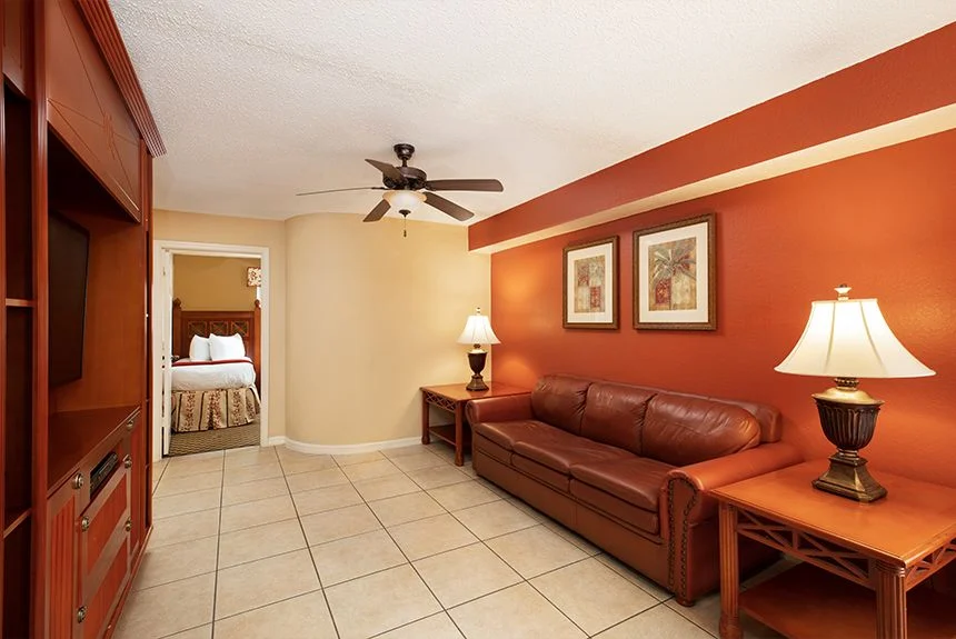 Living room of a Westgate Vacation Villas Resort two-bedroom villa with a leather sofa and an open door to a bedroom