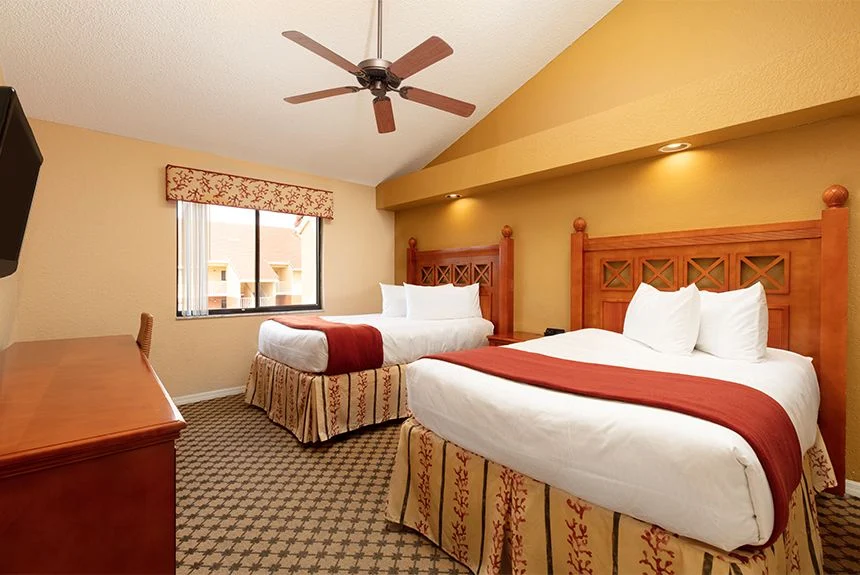 Two beds with carved wood headboards under a vaulted ceiling in a Westgate Vacation Villas Resort two-bedroom loft villa