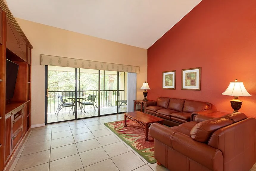 Living room of a Westgate Vacation Villas Resort two-bedroom villa with loft, with leather sofas and a balcony door