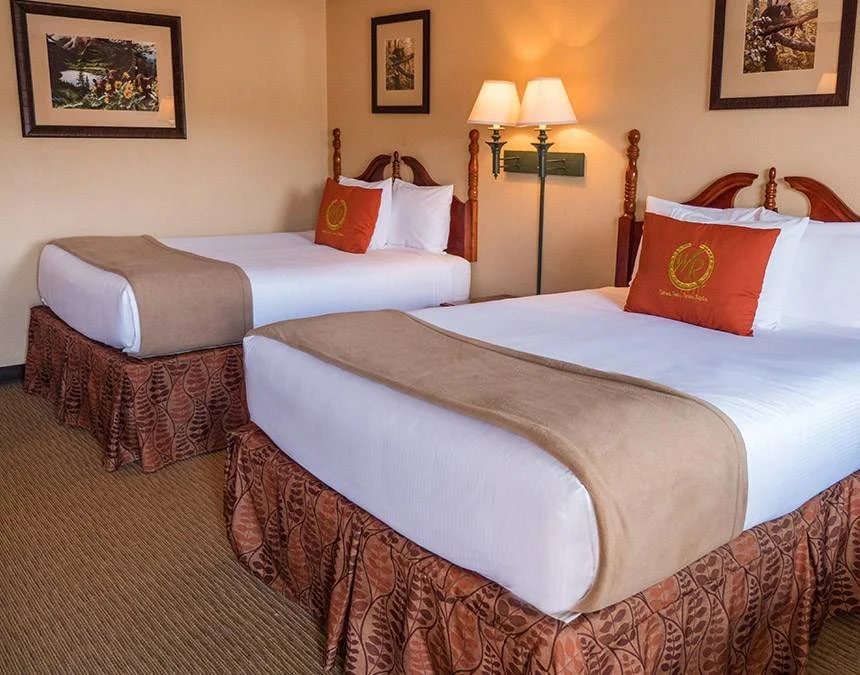 Deluxe hotel room with two beds, wooden headboards and red accent pillows