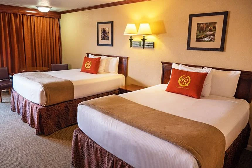 Two queen beds with red accent pillows and tan throws in a Wild Bear Inn double queen poolside guest room