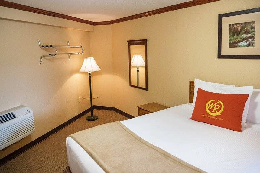Wild Bear Inn queen poolside guest room with a bed, floor lamp, wall mirror and air conditioning unit