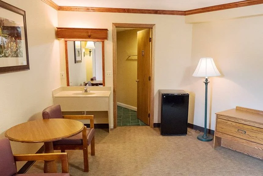 Vanity sink, mini fridge and a small table with chairs in a Wild Bear Inn queen poolside guest room