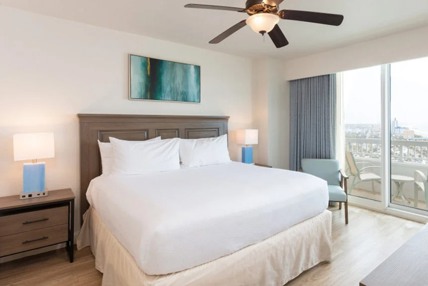 Bedroom in a Westgate Myrtle Beach Oceanfront two-bedroom ocean view with a bed, blue lamps and tall windows