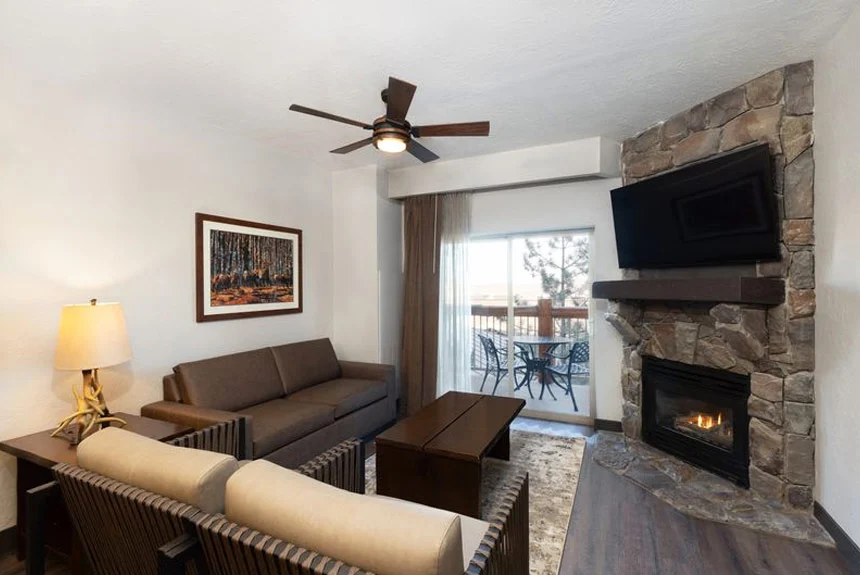 Living room of a Westgate Park City Resort & Spa one-bedroom grand villa with a stone fireplace and balcony door