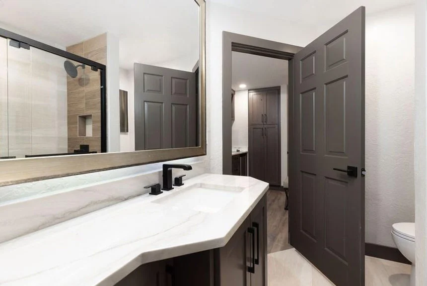 Bathroom of a Westgate Park City Resort & Spa studio villa with a white vanity, glass shower and dark doors