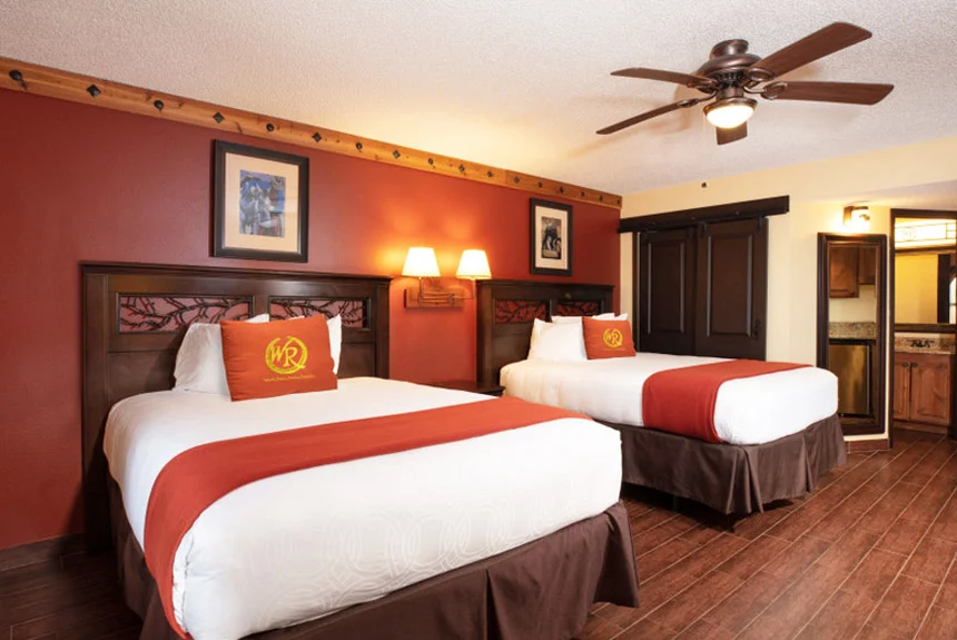 Westgate River Ranch Resort deluxe lodge suite with two beds, a red accent wall and a ceiling fan