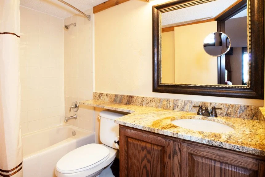 Bathroom of a Westgate River Ranch Resort lodge guest room with a granite vanity, framed mirror and bathtub