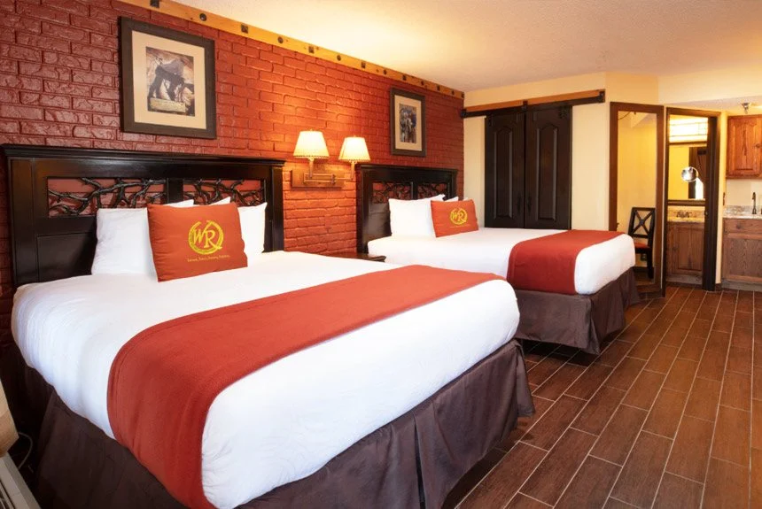 Westgate River Ranch Resort lodge guest room with two beds in red and white bedding and a brick accent wall