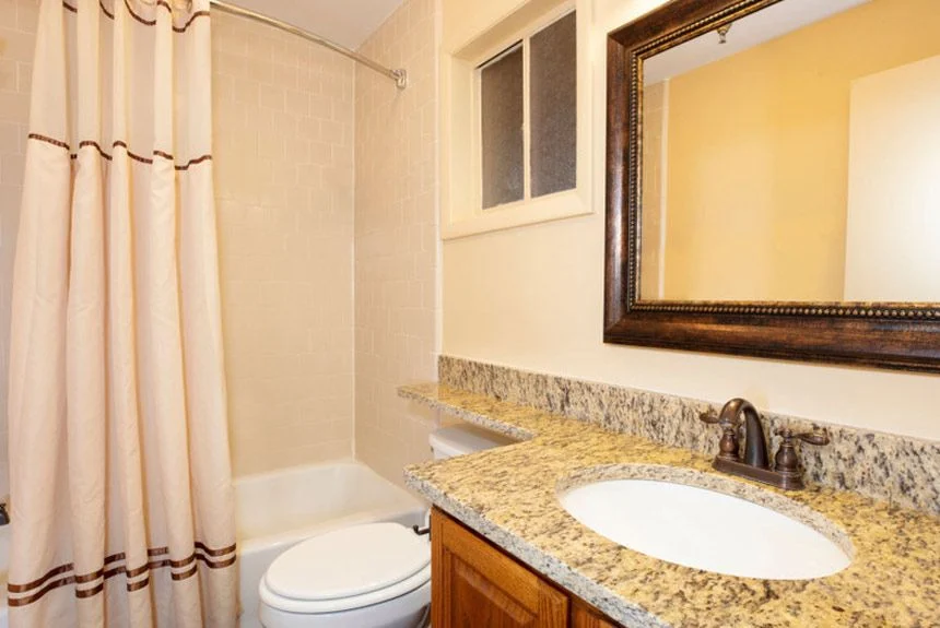 Bathroom of a Westgate River Ranch Resort lodge suite with a granite vanity, framed mirror and curtained tub