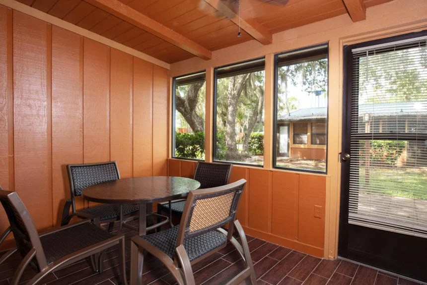Screened entry porch of a Westgate River Ranch Resort lodge suite with a table, chairs and a glass door