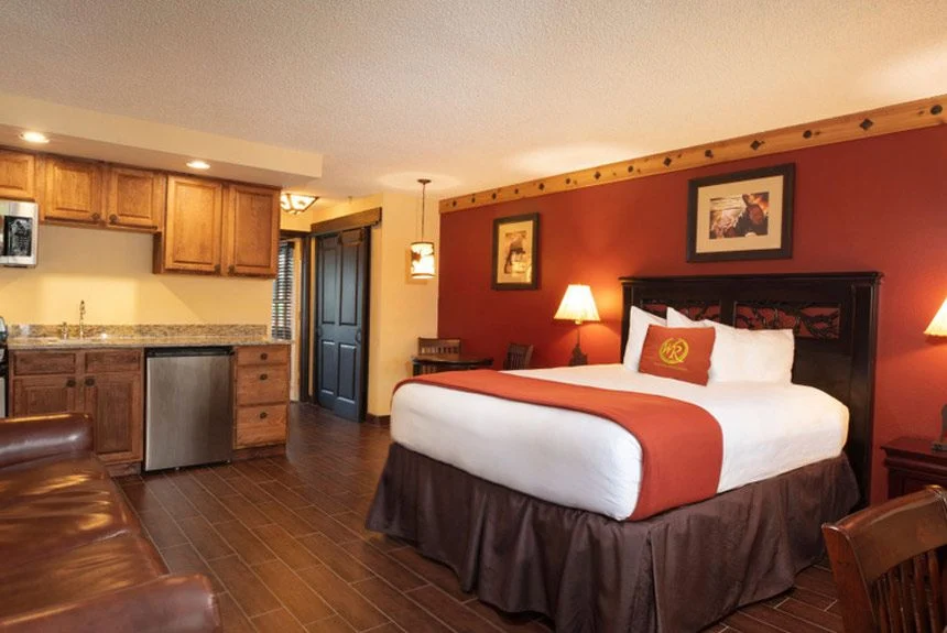 Westgate River Ranch Resort lodge suite with a bed, red accent wall and a kitchenette with wood cabinets