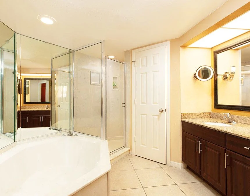 Bathroom of a Westgate Town Center Resort two-bedroom villa with a corner tub, glass shower and dark wood vanity