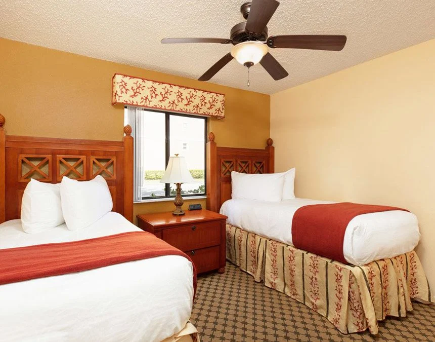Two beds with carved headboards under a ceiling fan in a Westgate Town Center Resort two-bedroom villa