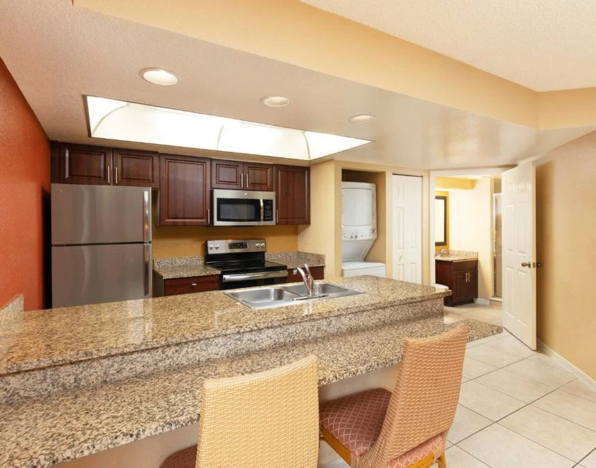 Kitchen of a Westgate Town Center Resort two-bedroom villa with a granite breakfast bar, stools and stainless appliances